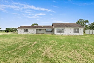 Rear view of property with a lawn and brick siding