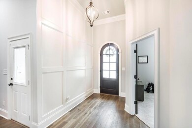 Entrance foyer featuring wood finished floors, crown molding, and baseboards