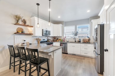 Kitchen with open shelves, stainless steel appliances, a peninsula, pendant lighting, and white cabinetry