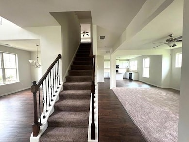 Staircase featuring a ceiling fan, wood finished floors, and a chandelier