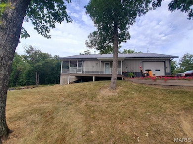 View of front of house with a garage, a wooden deck, a front yard, a sunroom, and a metal roof