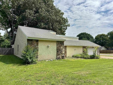 View of property exterior with stone siding, a garage, and driveway