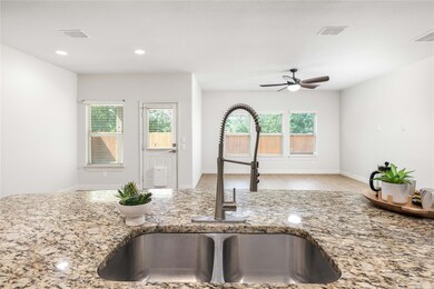 Kitchen view of a sink, a ceiling fan, light ston