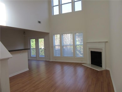 Unfurnished living room with a fireplace with raised hearth, plenty of natural light, dark wood-style flooring, and a high ceiling