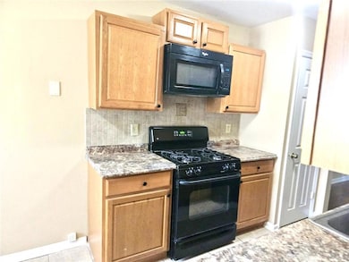 Kitchen featuring black appliances, backsplash, light brown cabinets, and light tile patterned floors