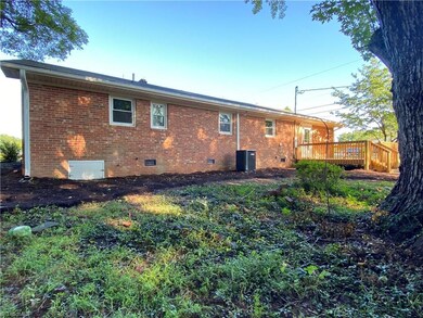 Back of home showing crawl space door, new heat pump, and new deck