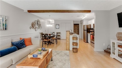Living room featuring light wood finished floors, crown molding, and beamed ceiling