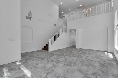 Unfurnished living room with a towering ceiling, arched walkways, a chandelier, light marble finish flooring, and recessed lighting