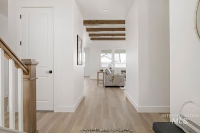 Corridor featuring beam ceiling, light wood-type flooring, and stairway