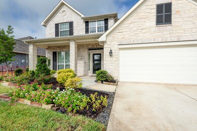 Landscaping & a covered front porch invite you to the entrance.