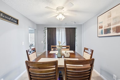 Dining area with ceiling fan, a textured ceiling, and light carpet