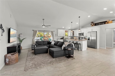 Living room featuring ceiling fan and high vaulted