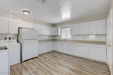 Kitchen with freestanding refrigerator, washer, an