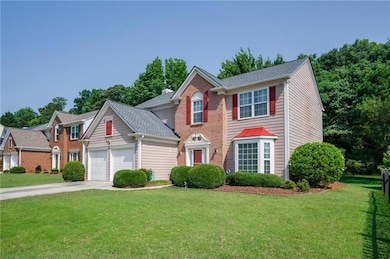 Colonial home featuring a garage, driveway, a front lawn, and roof with shingles