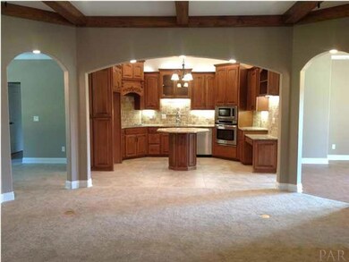Great room is open with lighted arch way that shows the gorgeous kitchen cabinets, travertine backsplash and granite counter tops.