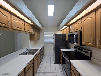 Kitchen with stainless steel appliances, light tile patterned floors, and light countertops