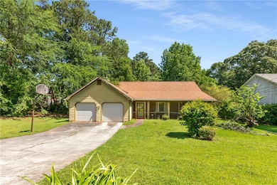 Ranch-style house featuring covered porch, a garage, and a front lawn