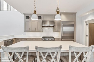 Kitchen featuring a breakfast bar, stainless steel appliances, tasteful backsplash, ventilation hood, and gray cabinets