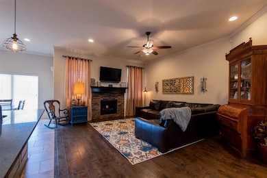 Living room featuring a ceiling fan, a fireplace, dark wood-style floors, recessed lighting, and crown molding