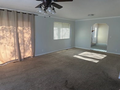 Unfurnished room with arched walkways, carpet floors, ornamental molding, and a ceiling fan