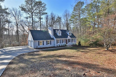New england style home featuring a chimney, driveway, and an attached garage