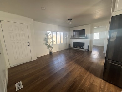 Unfurnished living room featuring dark wood-type flooring and baseboards