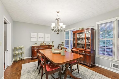 Dining space with a chandelier, dark wood-type flooring, and a textured ceiling