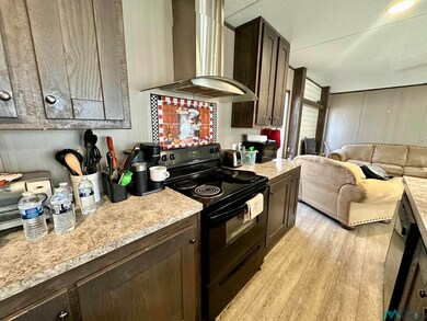 Kitchen with wall chimney exhaust hood, black range with electric cooktop, dark brown cabinets, light countertops, and a textured ceiling