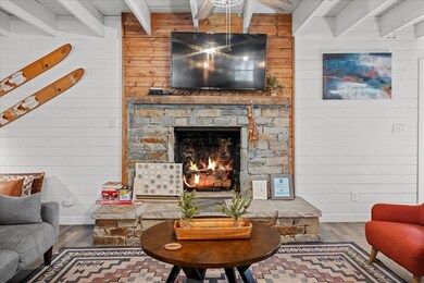 Living area with wooden walls, beam ceiling, a fireplace, and wood finished floors