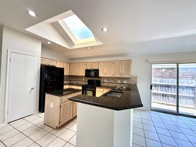 Kitchen featuring light brown cabinetry, a skylig