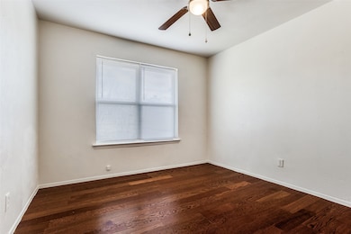 Empty room featuring dark wood-style floors and ceiling fan