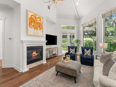 Living area with wood finished floors, a glass covered fireplace, beamed ceiling, and high vaulted ceiling