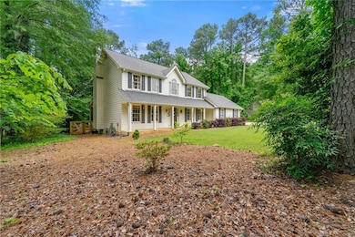 Colonial inspired home with a porch, roof with shingles, and a front lawn