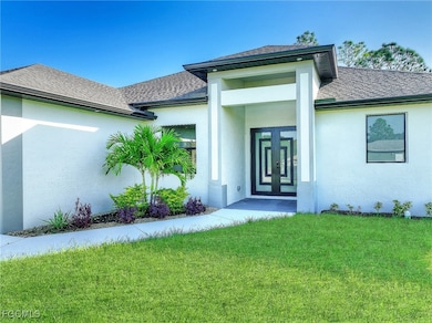 Doorway to property with a yard, stucco siding, roof with shingles, and french doors