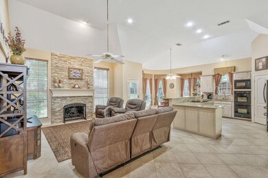 Tiled living room with high vaulted ceiling, sink, a fireplace, and ceiling fan