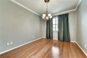 Empty room featuring crown molding, an inviting chandelier, and dark wood-type flooring