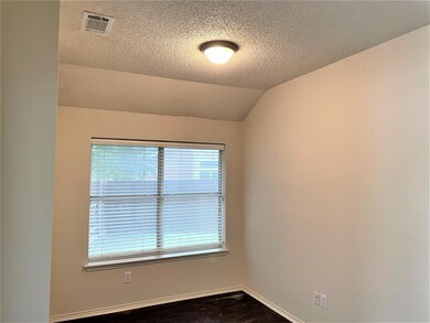 Unfurnished room featuring dark hardwood / wood-style flooring, a textured ceiling, and vaulted ceiling