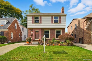 Colonial home with a chimney, a front yard, and brick siding