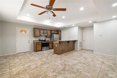 Kitchen with light stone countertops, stainless steel appliances, a raised ceiling, and a kitchen bar