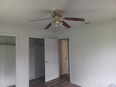 Unfurnished bedroom featuring multiple closets, dark wood-style floors, baseboards, and ceiling fan