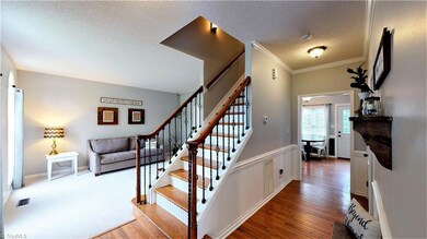 Staircase w/wrought-iron style railing and wood treads makes for a grand entrance! Updated color scheme gives a more modern appearance.