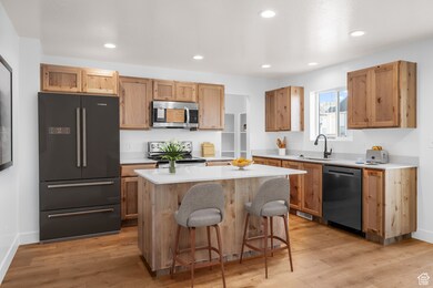 Kitchen with stainless steel appliances, light countertops, a kitchen bar, recessed lighting, and a kitchen island