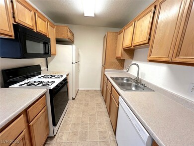 Kitchen with white appliances, a textured ceiling,