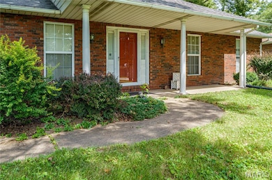 Doorway to property featuring a porch, and brick siding