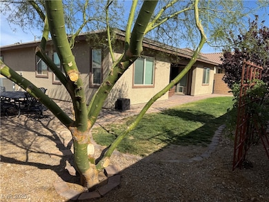 Back of house featuring a lawn, stucco siding, and