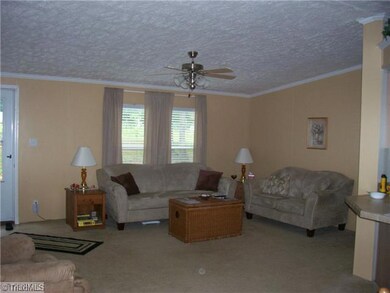 Living Room. Wonderful Great Room offering textured ceiling, carpeted floors, neutral color scheme, ceiling fan, insulated windows, and crown molding.