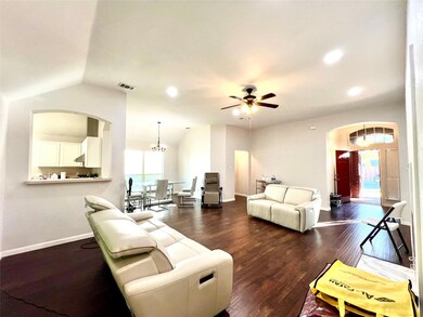 Living room with ceiling fan with notable chandelier, dark wood-type flooring, and vaulted ceiling