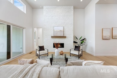 Living room featuring a brick fireplace, light wood-style flooring, a high ceiling, and recessed lighting