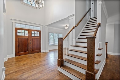 Foyer featuring a high ceiling, wood finished floors, ornamental molding, stairway, and a chandelier