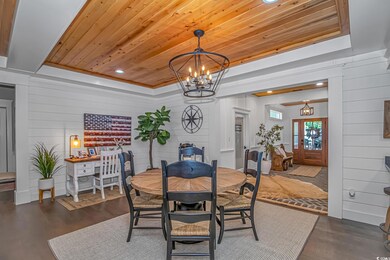 Dining area with a chandelier, dark wood finished floors, wooden ceiling, a raised ceiling, and wood walls